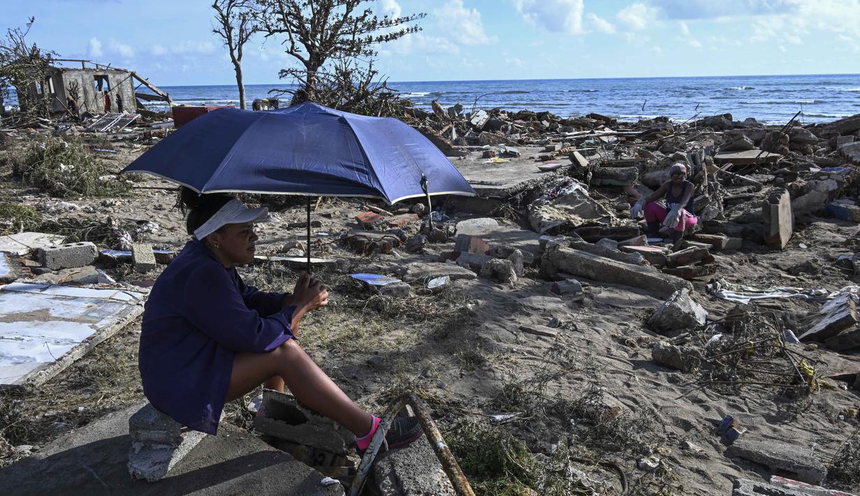 Warga beristirahat di tengah puing-puing rumah yang rusak akibat Badai Melissa di desa Boca de Dos Rios, provinsi Santiago de Cuba, Kuba, pada Kamis 30 Oktober 2025. Pihak berwenang mengatakan sekitar ratusan ribu warga masih berada di tempat penampungan. (YAMIL LAGE/AFP)