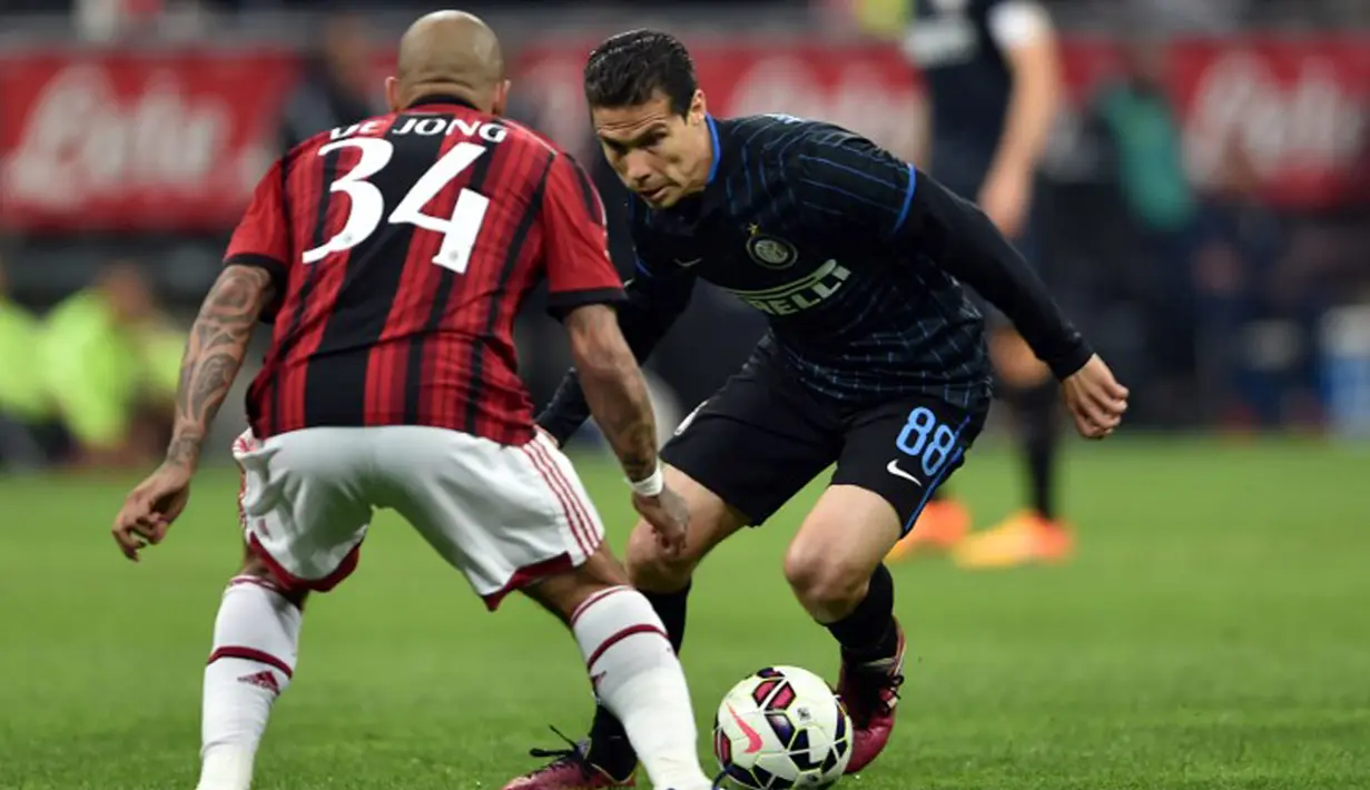 Gelandang Inter Milan,  Hernanes (kanan) berusaha melewati gelandang AC Milan Nigel De Jong  pada laga serie A di Stadio Giuseppe Meazza, Senin (20/4/2015). Inter Milan bermain imbang 0-0 dengan AC Milan. (AFP PHOTO/Giuseppe Cacace)