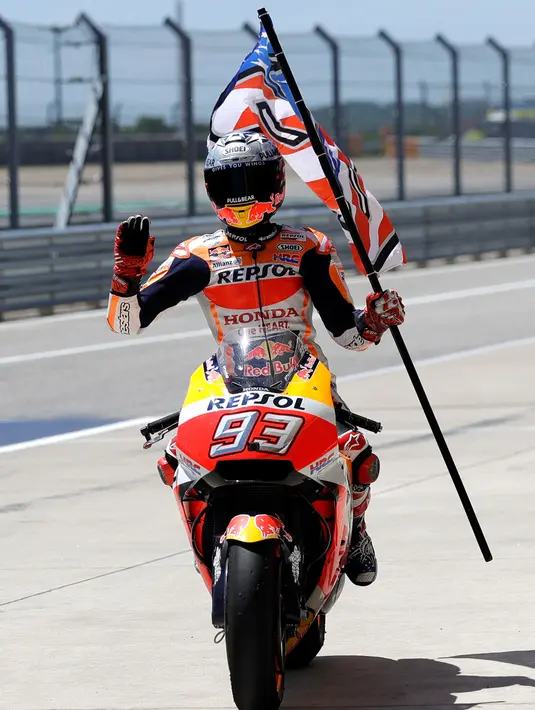 Pembalap Repsol Honda, Marc Marquez membawa bendera saat berselebrasi usai memenangi balapan MotoGP Amerika di Circuit of the Americas (COTA), Austin, Minggu (22/4). Hasil ini menjadi kemenangan keenam Marquez secara beruntun di Amerika. (AP/Eric Gay)