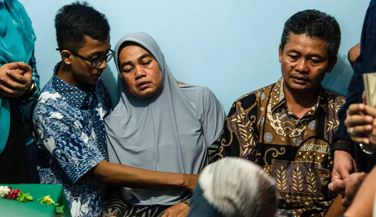 Orangtua dari korban jatuhnya pesawat Lion Air JT 610 Jannatun Cintya Dewi duduk depat peti jenazah anaknya sebelum pemakaman di kediaman kawasan Sukodono, Sidoarjo, Jawa Timur, Kamis (1/11). (JUNI KRISWANTO / AFP)