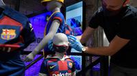 Penjaga toko memasang masker berlogo Barcelona ke Manekin di Toko Asesoris Barcelona, Senin (25/5/2020). Di tengah pandemi virus Corona, Barcelona menjual masker dengan harga 18 euro atau sekitar Rp 291 ribu. (AFP/Lluis Gene)