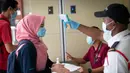 Seorang wanita diperiksa suhu tubuhnya oleh seorang petugas keamanan di pintu masuk pusat perbelanjaan di Kuala Lumpur, Malaysia, Senin, (4/5/2020). (AP/Vincent Thian)