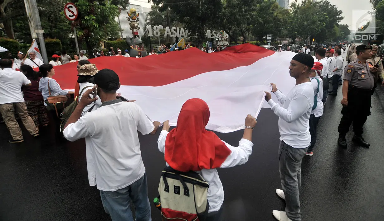 Massa yang tergabung dalam Gerakan Jaga Indonesia (GJI) membentangkan bendera Merah Putih raksasa saat menggelar aksi di depan Balai Kota, Jakarta, Kamis (29/11). (Merdeka.com/Iqbal S. Nugroho)