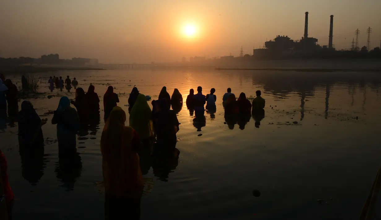 Umat Hindu India mengambil bagian dalam ritual pemujaan dewa matahari selama Festival Chhath Puja di tepi sungai Sabarmati, Ahmedabad, Selasa (13/11). Festival Hindu kuno ini dilakukan sebagai bentuk terima kasih kepada Dewa Matahari (SAM PANTHAKY/AF/AFP)