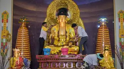 Tradisi ini menjadi simbol penyucian hati dan pikiran umat Buddha sebagai persiapan menyambut lembaran baru di tahun mendatang. Tampak dalam foto, warga membersihkan patung Buddha dalam persiapan perayaan Tahun Baru Imlek 2577 Kongzili di Vihara Buddhayana, Surabaya, Jawa Timur pada Senin 9 Februari 2026. (JUNI KRISWANTO/AFP)