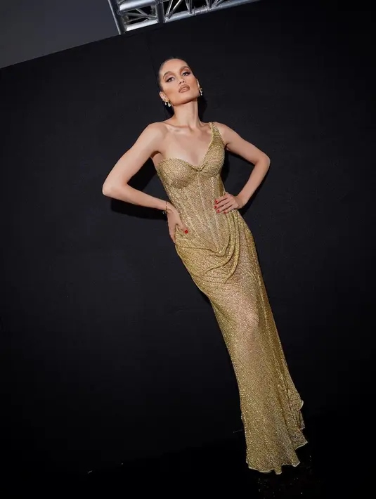 Gaun yang dikenakan Cinta Laura ini megah bernuansa keemasan. Ditaburi payet dan bebatuan yang berkilauan dengan bagian tali asimetris. [Foto: Instagram/claurakiehl]