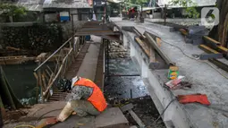 Pekerja menyelesaikan proyek pembangunan jembatan penghubung antarkampung di kawasan Pondok Pinang, Jakarta, Jumat (13/12/2019).  Jembatan yang menghubungkan permukiman di daerah Pondok Pinang dengan kawasan Bintaro tersebut ditargetkan rampung pada akhir Desember. (Liputan6.com/Faizal Fanani)