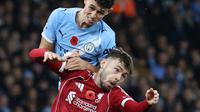 Duel Conor Bradley dari Liverpool (bawah) dengan Phil Foden dari Man City saat kedu tim bertemu di Etihad Stadium, Minggu (9/11/2025). (Darren Staples / AFP)