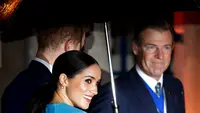 Meghan Markle memegang lengan Pangeran Harry yang memayunginya saat tiba di Endeavour Fund Awards, London, Inggris, Kamis (5/3/2020). Meghan Markle memilih tampil dengan dress rancangan Victoria Beckham. (AP Photo/Kirsty Wigglesworth)