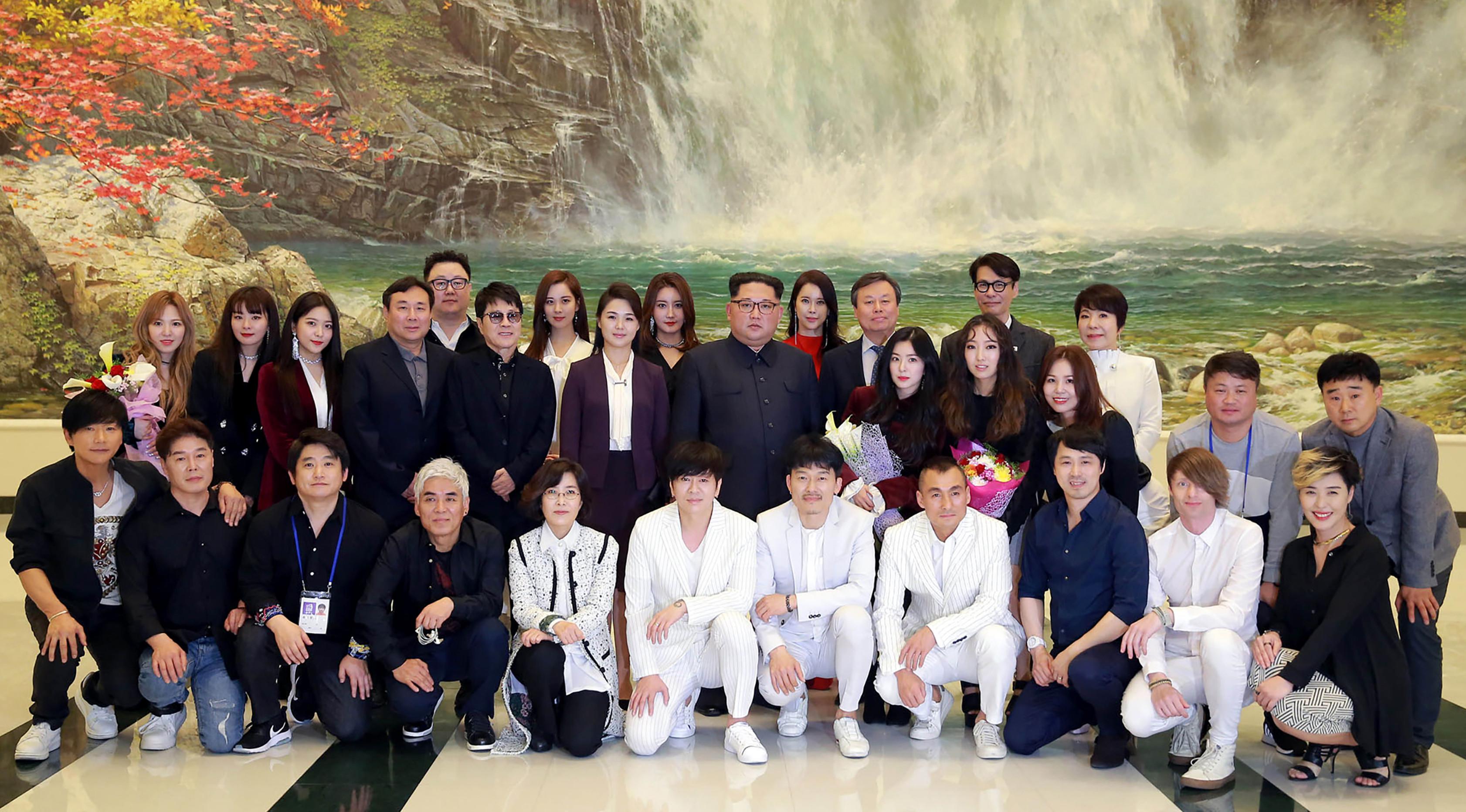 Pemimpin Korea Utara Kim Jong-Un (tengah) dan istrinya Ri Sol-Ju (tengah kiri) berfoto bersama sejumlah bintang K-pop dan musisi dari Korea Selatan di East Pyongyang Grand Theatre, Korea Utara (4/1). (AFP Photo/KCNA)