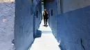Seorang wanita berjalan di sepanjang gang kecil, Kota Chefchaouen, Maroko, (1/5).Maroko termasuk negara yang bebas visa bagi turis Indonesia membuat Maroko jadi pilihan tepat ketika kamu ingin melakoni travel dengan bugdet minim. (FADEL SENNA / AFP)
