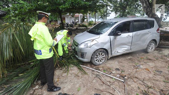 Petugas melakukan identifikasi mobil yang rusak akibat terjangan tsunami di Tanjung Lesung Beach Club, Pandeglang, Banten, selasa (25/12). Indentifikasi dilakukan untuk mencocokan kepemilikan kendaraan dengan para korban tsunami. (Merdeka.com/Arie Basuki)