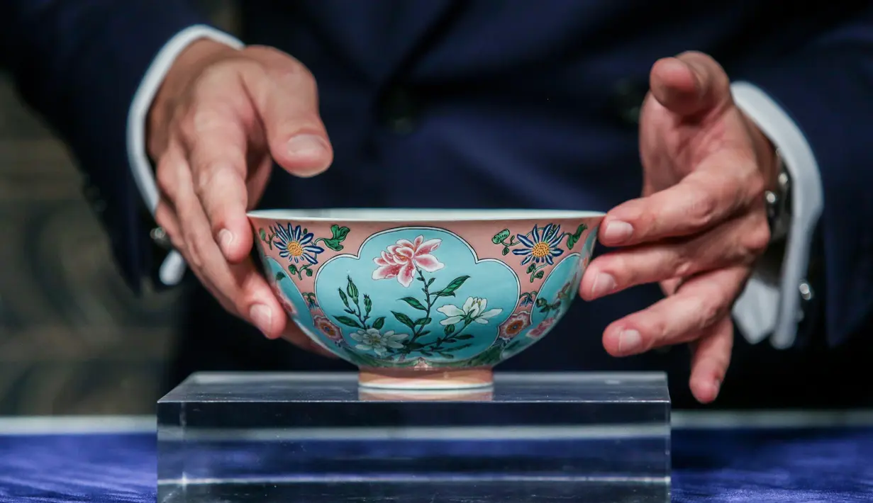 Wakil Kepala Sotheby Asia, Nicolas Chow memegang mangkuk langka dari masa Dinasti Qing pada pratinjau media di Hong Kong, Selasa (3/4). Mangkuk antik kepunyaan Kaisar Kangxi itu terjual dengan harga USD 30,4 juta (Rp 417 miliar). (ISAAC LAWRENCE/AFP)