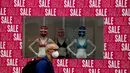 Seorang pria mengenakan masker berjalan melewati jendela toko di London, Selasa (14/7/2020). Pemerintah Inggris menuntut warga mengenakan masker di toko-toko di tengah pandemi COVID-19. (AP Photo/Frank Augstein)