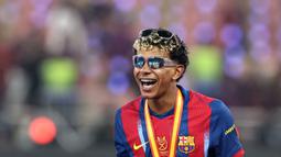 Pemain Barcelona, Lamine Yamal mengenakan dua kacamata saat merayakan gelar juara Piala Super Spanyol 2026 setelah mengalahkan Real Madrid dengan skor 3-2 dalam laga final yang berlangsung di King Abdullah Stadium, Jeddah, Arab Saudi, Minggu (11/01/2026) waktu setempat. (AFP/Fadel Senna)