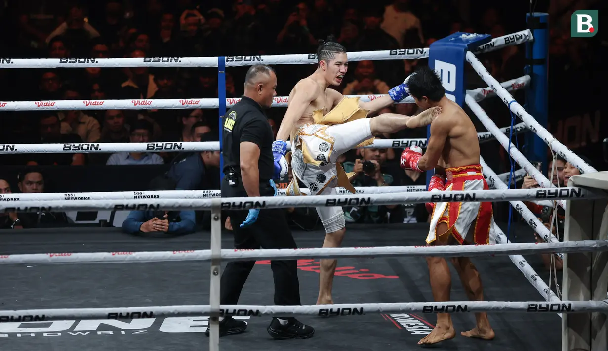 Petarung Malaysia, Ammarul Shafiq, melepaskan tendangan keras ke bagian rahang kiri petarung Indonesia, Serieal Effendy pada pertandingan Byon Combat Showbiz Vol. 6 di Tennis Indoor Senayan, Jakarta, Sabtu (22/10/2025). (Bola.com/M Iqbal Ichsan)