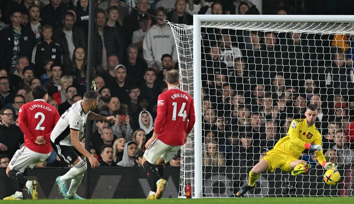 Kiper Manchester United (MU) David de Gea menyelamatkan tembakan dari penyerang Fulham Carlos Vinicius pada pekan ke-16 Liga Inggris 2022/2023 di Craven Cottage, London, Minggu (13/11/2022). Gol Alejandro Garnacho di menit akhir memastikan kemenangan 2-1 Setan Merah atas Fulham. (Photo by Glyn KIRK / AFP)