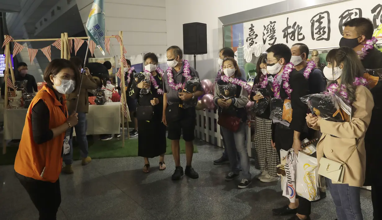 Pemandu wisata berbicara kepada  kelompok pertama wisatawan asing setelah kedatangan mereka di Bandara Internasional Taoyuan di Taoyuan, Taiwan Utara, Kamis (13/10/2022). Pusat Komando Epidemi (CECC) Pemerintah Taiwan meniadakan karantina dan menggantinya dengan pemantauan kesehatan mandiri selama 7 hari. (AP Photo/Chiang Ying-ying)