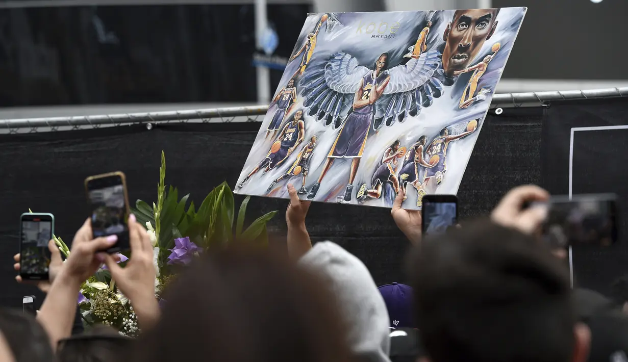 ara fans membawa foto yang menampilkan pebasket NBA Kobe Bryant di luar Staples Center di luar Staples Center, Los Angeles (26/1/2020). Putri Bryant yang berusia 13 tahun, Gianna Bryant juga ikut meninggal dunia dalam insiden tersebut. (AP Photo/Chris Pizzello)