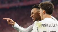 Penyerang Real Madrid, Kylian Mbappé (kiri), merayakan gol yang membawa skor menjadi 2-3 bersama rekan setimnya, Arda Guler, dalam pertandingan leg kedua perempat final Liga Champions 2025/2026 antara Bayern Munich dan Real Madrid di Munich, Jerman selatan, pada 15 April 2026. (Alexandra BEIER / AFP)