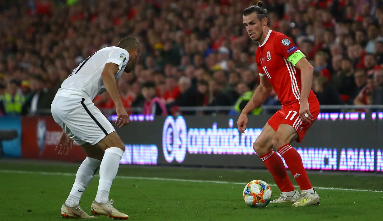 Gelandang Wales, Gareth Bale, berusaha melewati bek Azerbaijan, Pavlo Pashayev, pada laga Kualifikasi Piala Eropa 2020 di Cardiff City Stadium, Cardiff, Jumat (6/9). Wales menang 2-1 atas Azerbaijan. (AFP/Geoff Caddick)
