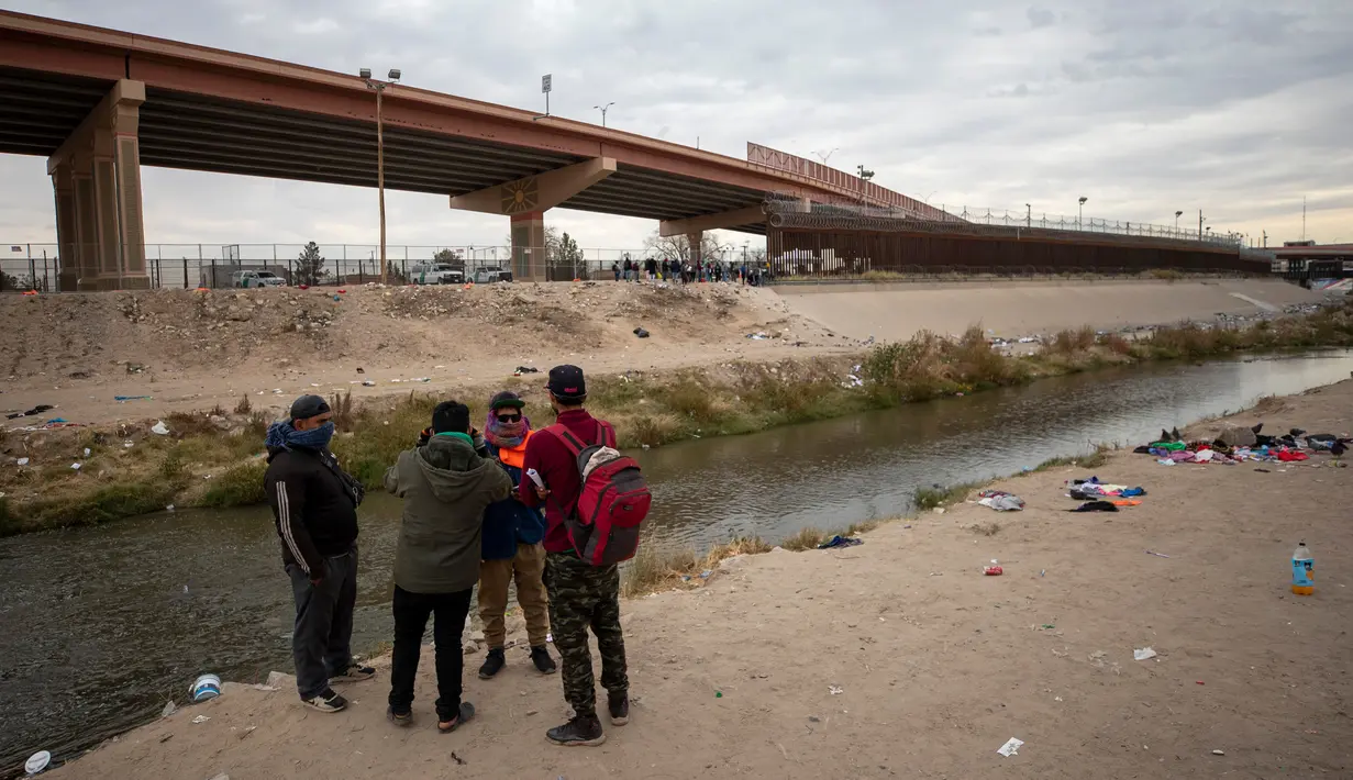 Sekelompok kecil imigran mendiskusikan apakah akan menyeberangi Rio Grande atau tidak dari Ciudad Juarez, Meksiko, dan menyerah kepada Patroli Perbatasan di El Paso, Texas, 18 Desember 2022. Kota-kota perbatasan Texas bersiap menghadapi lonjakan sebanyak 5.000 imigran baru setiap hari yang melintasi perbatasan AS-Meksiko karena pembatasan imigrasi era pandemi berakhir minggu ini. (AP Photo/Andres Leighton)
