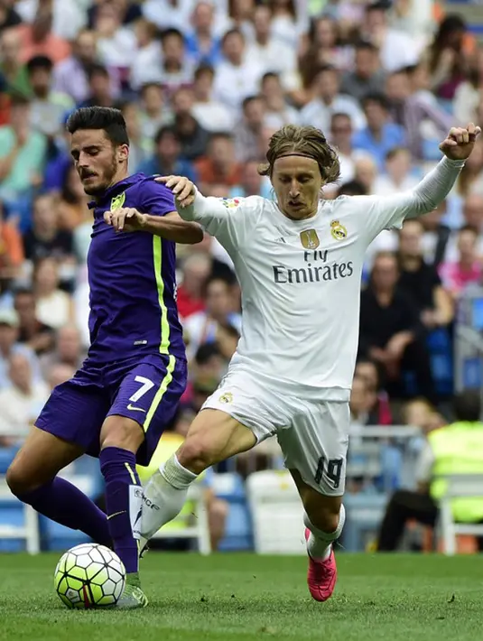 Gelandang malaga, Juan Carlos Perez Lopez (kiri) berusaha mengontrol bola dari kejaran gelandang Luca Modric pada Liga Spanyol di Santiago Bernabeu, Madrid, (26/9/2015). Madrid bermain imbang atas malaga dengan skor 0-0. (AFP PHOTO/PIERRE-PHILIPPE Marcou)