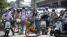 Para komuter yang mengenakan masker menunggu di persimpangan kawasan pusat bisnis di Beijing, China, Selasa (31/5/2022). Otoritas Shanghai mengatakan mereka akan mengambil beberapa langkah besar pada Rabu untuk membuka kembali kota terbesar di China setelah dua bulan penguncian COVID-19. (AP Photo/Mark Schiefelbein)