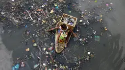 Seorang anak duduk di perahu darurat saat mengumpulkan sampah untuk bahan daur ulang di sebuah sungai yang tercemar di kota navotas, Manila, Kamis (2/7/2015). Daur ulang bertujuan untuk mengurangi tingkat pencemaran sungai. (REUTERS/Romeo Ranoco)