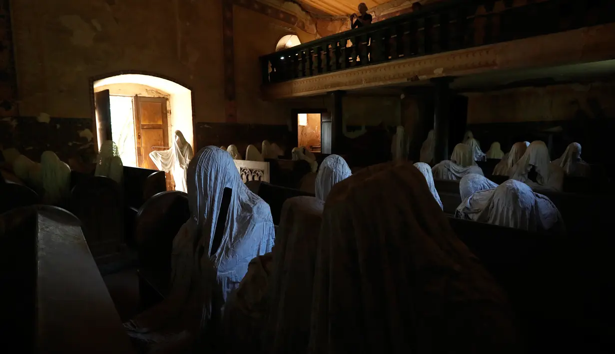 Gambar pada 30 Agustus 2018 menunjukkan  turis Prancis mengambil gambar patung-patung serupa hantu yang ditampilkan di Gereja St George, Lukova, Republik Ceko. Ibadah terakhir yang diadakan di dalam gereja berlangsung di tahun 1968. (AP/Petr David Josek)