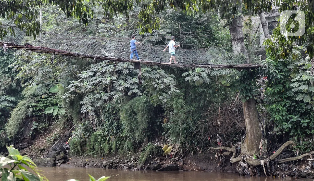 Anak-anak melintasi jembatan gantung yang sudah tidak layak di kawasan Srengseng Sawah, Jakarta, Sabtu (12/6/2021). Kondisi jembatan gantung yang menjadi akses warga dari Cimanggis menuju Srengseng Sawah atau sebaliknya tersebut beralaskan bambu serta seng. (merdeka.com/Iqbal S. Nugroho)