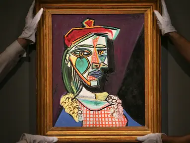 Petugas rumah lelang Sotheby menata lukisan Pablo Picasso bertema Marie-Therese Walter pada sesi pemotretan di London, Rabu (22/2). Lukisan yang akan dilelang ini diperkirakan nilainya mencapai US$ 50 juta atau Rp 685 miliar. (Daniel LEAL-OLIVAS/AFP)