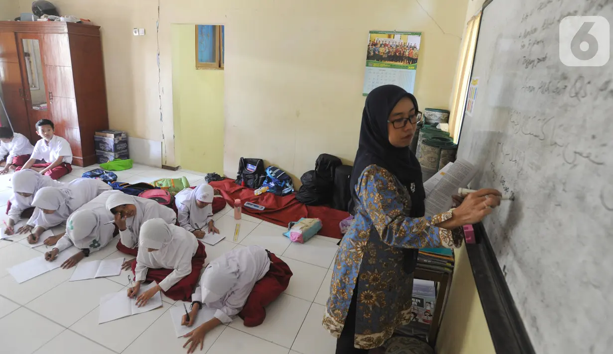 Siswa kelas VI  Madrasah Ibtidaiyah Mathlaul Anwar Ciangsana melakukan proses belajar mengajar tanpa meja dan kursi pada bangunan majelis taklim di Tenjolaya, Bogor, Selasa(22/10/2019).  Kegiatan itu dilakukan karena dua dari lima ruang kelas yang ada sudah rusak dan lapuk. (merdeka.com/Arie Basuki)