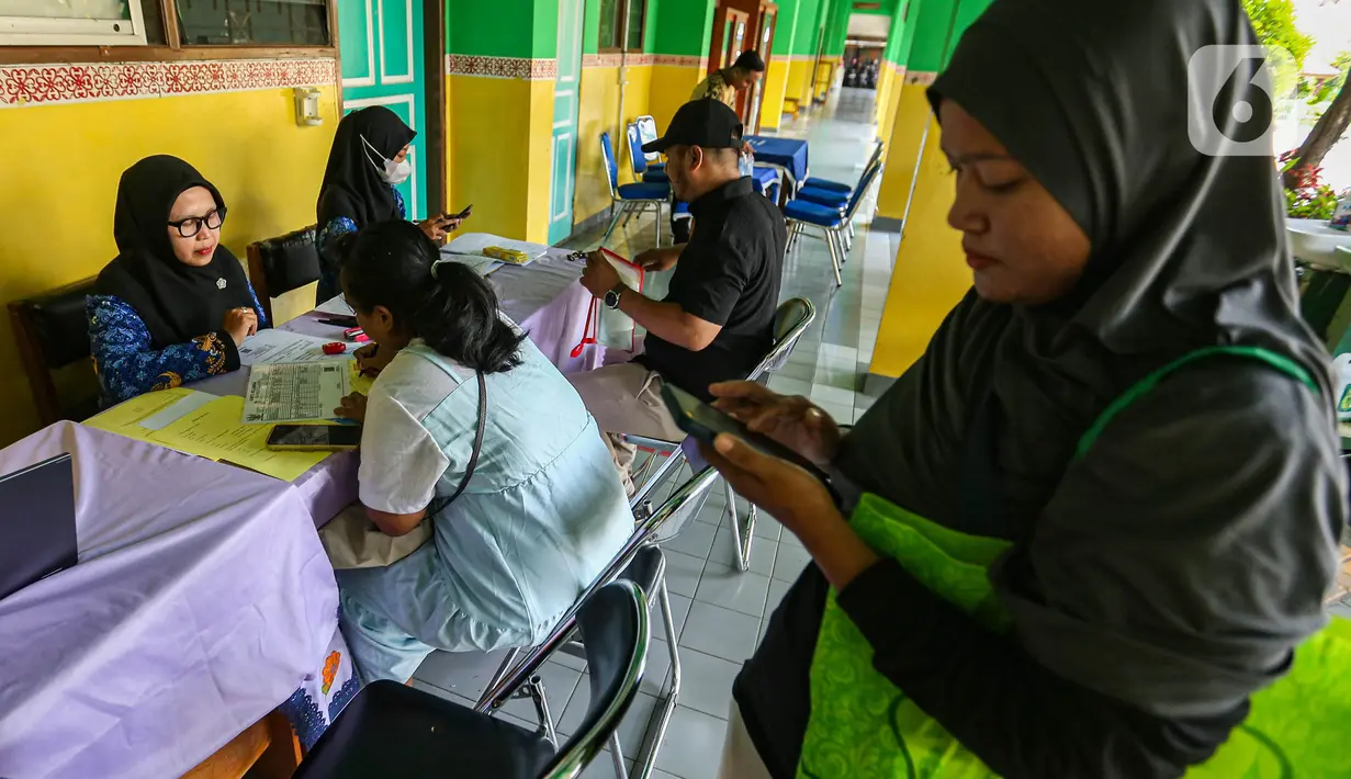Petugas melayani orang tua calon peserta didik saat pendaftaraan Penerimaan Peserta Didik Baru (PPDB) di SD Grogol Selatan 08, Jakarta, Senin (20/5/2024). (Liputan6.com/Angga Yuniar)