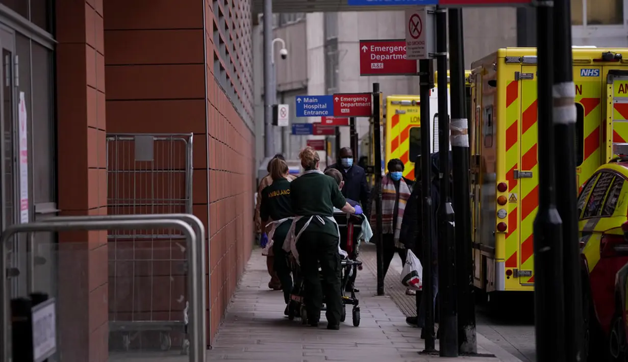 Seorang pasien didorong dengan troli setelah tiba dengan ambulans di luar Rumah Sakit Royal London, Inggris, 6 Januari 2022. Inggris memangkas waktu isolasi pasien COVID-19 dari 10 menjadi 7 hari karena kekurangan tenaga kesehatan akibat lonjakan kasus yang dipicu Omicron. (AP Photo/Matt Dunham)