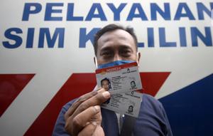 Warga menunjukkan SIM di Pelayanan SIM Keliling, Tangerang Selatan, Banten, Jumat (7/8/2020). Ditlantas Polda Metro Jaya memberi dispensasi bagi pemilik SIM yang masa berlakunya habis di masa pandemi COVID-19 bisa memperpanjang sampai akhir Agustus 2020. (merdeka.com/Dwi Narwoko)