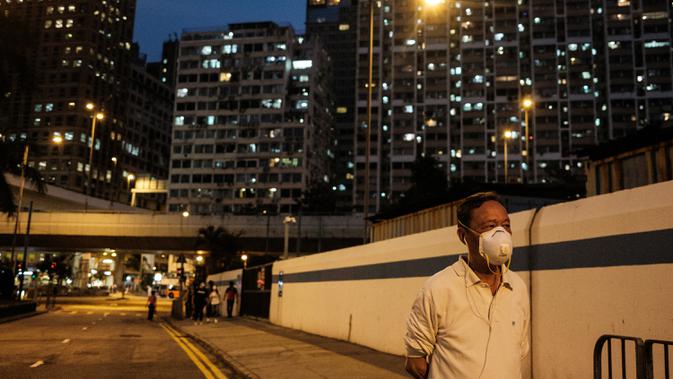 Seorang pria memakai masker berjalan di sepanjang jalan di Hong Kong (21/4/2020). Kepala eksekutif Carrie Lam mengatakan langkah-langkah jarak sosial dan beberapa pembatasan bisnis akan berlanjut selama dua minggu hingga setidaknya 7 Mei. (AFP/Anthony Wallace)