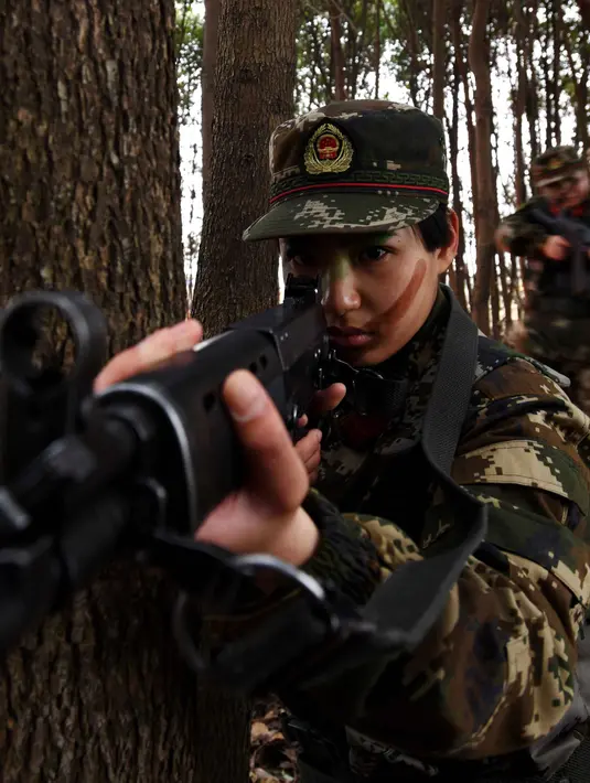 Tentara wanita China melakukan simualisi perang di tengah hutan saat melakukan latihan militer jelang Hari Perempuan Internasional di Hefei, China (6/4). (AFP)