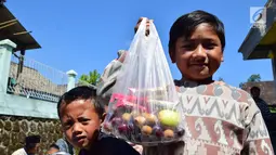Seorang anak menunjukkan makanan di Kabupaten Boyolali, Kamis (3/5). Tradisi ini Sebagai perayaan menyambut datangnya bulan ramadan, kemudian dilanjutkan makan bersama di pertigaan jalan desa. (Liputan6.com/Gholib)