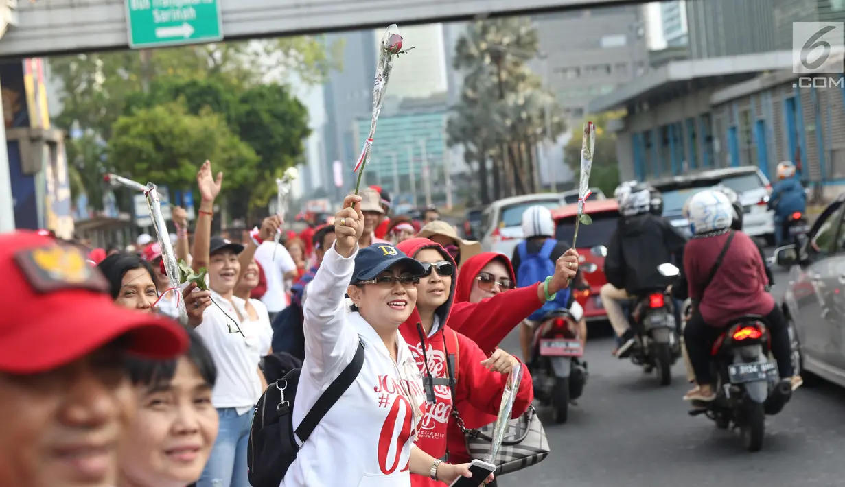 Relawan Jokowi saat membagikan bunga mawar di Kawasan Sarinah, Jakarta, Minggu (29/9/2019). Aksi bagi bunga tersebut merupakan aksi damai kami bersama Jokowi. (Liputan6.com/Angga Yuniar)