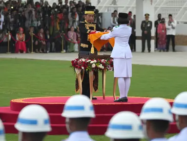 Presiden Joko Widodo (kiri tengah) menyerahkan bendera Merah-Putih kepada seorang pembawa bendera untuk dikibarkan dalam upacara Peringatan Kemerdekaan ke-79 Republik Indonesia di Istana Kepresidenan yang baru di Ibu Kota Negara, Nusantara, Sabtu, 17 Agustus 2024. (AP Photo/Achmad Ibrahim)