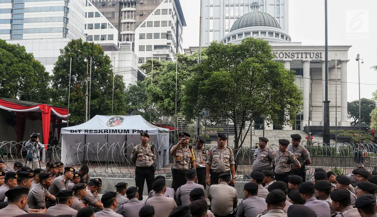 Polisi berjaga menjelang sidang perdana MK Pemilu 2019 di halaman depan Gedung Mahkamah Konstitusi, Jakarta, Jumat, (14/6/2019). Polri kembali menerapkan skema pengamanan empat lapis atau ring untuk mengawal jalannya sidang. (Liputan6.com/Johan Tallo)