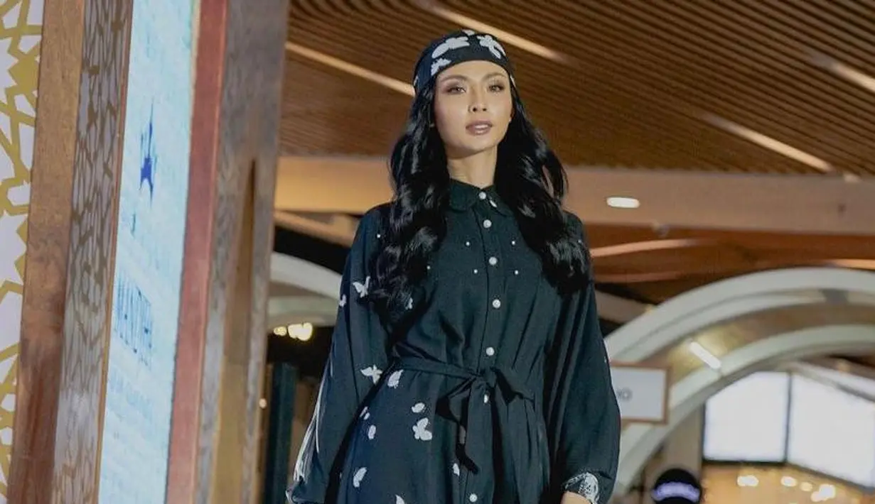 Begini potret Miss Grand Indonesia 2022, Andina Julie membawakan koleksi modest wear bertajuk ‘Timeflies’ milik Ivan Gunawan. Gamis warna hitam ini memiliki aksen kancing dan motif kupu-kupu. (Instagram/mandjha.ivangunawan).