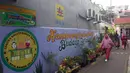 Warga melintas di depan mural bertema budaya Betawi di kawasan Kampung Sentra Kreatif, RW 006 Kota Bambu Selatan, Jakarta, Rabu (3/11/2021). Pengembangan kawasan ini juga untuk memberdayakan potensi perekonomian masyarakat, baik kuliner, jasa, dan tanaman obat. (Liputan6.com/Herman Zakharia)
