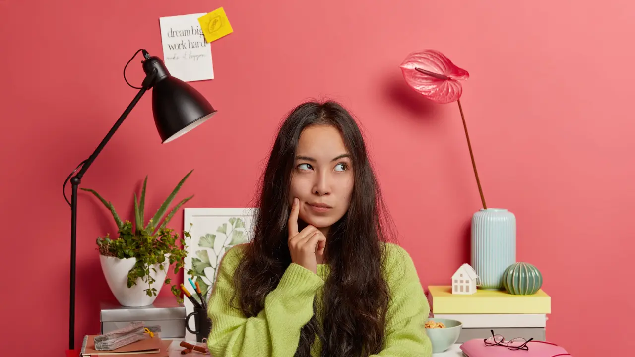 Seorang perempuan berambut panjang sedang berpikir dengan memegang pipinya menggunakan telunjuk (Foto Dok: Freepik/wayhomestudio)