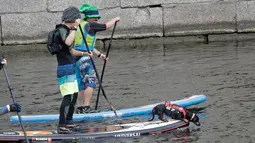 Seorang peserta membawa anjinya diatas Stand Up Paddle (SUP) saat mengikuti Surfing festival di St.Petersburg, Rusia (8/7). Paddle Board ini tidak mengandalkan angin kencang dan ombak yang dahsyat. (AP Photo / Dmitri Lovetsky)