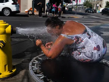 Stephanie Williams, mendinginkan diri dengan air dari hidran di daerah Skid Row di Los Angeles, Rabu (31/8/2022). Peringatan panas berlebihan meluas ke seluruh California Selatan dan utara ke Central Valley pada Rabu, diperkirakan akan menyebar ke California Utara di akhir minggu. (AP Photo/Jae C.Hong)