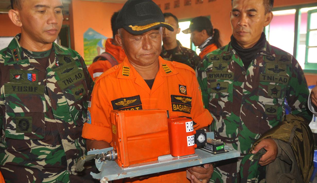 Petugas dari Basarnas memegang sebuah kotak hitam atau Black Box dari helikopter Basarnas yang jatuh di Temanggung, Jawa Tengah (3/7). Black Box tersebut akan dibawa dan dikaji oleh KNKT dan Basarnas. (AP Photo)