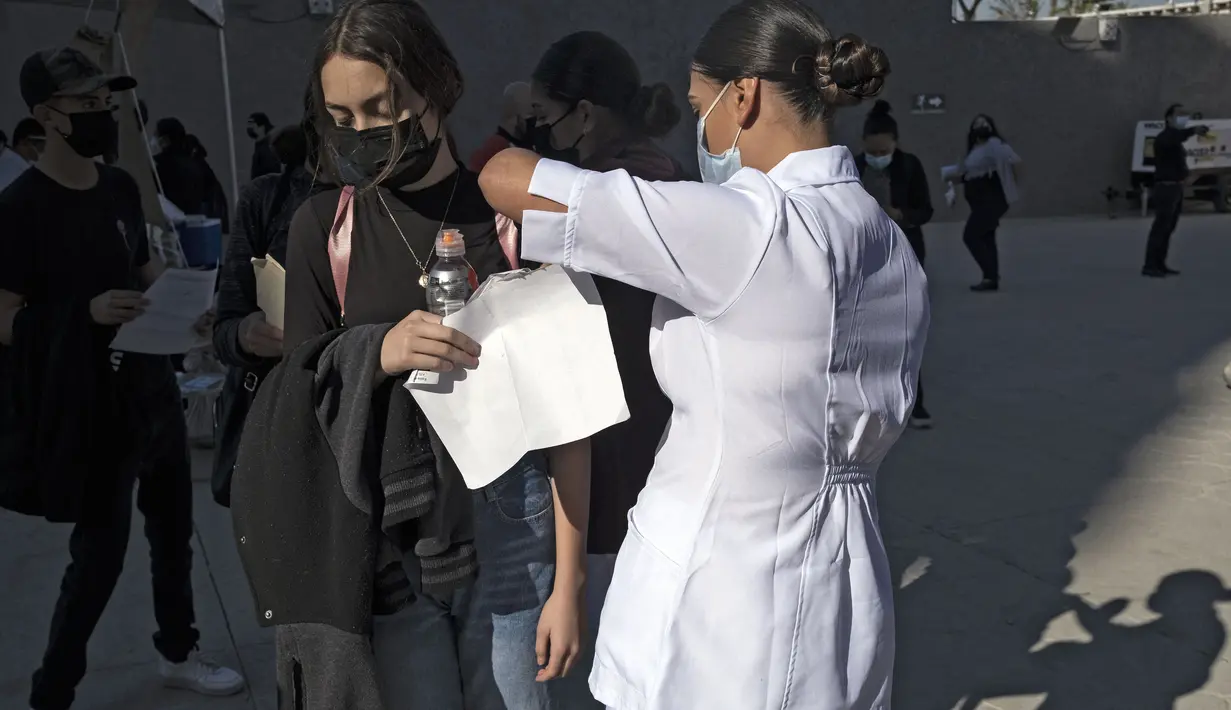 Seorang anak divaksin COVID-19 dalam program vaksinasi untuk anak-anak berusia 15 hingga 17 tahun di Stadion Caliente, Tijuana, Baja California, Meksiko, 24 November 2021. Meksiko bersiap menghadapi gelombang keempat infeksi virus corona COVID-19. (Guillermo Arias/AFP)