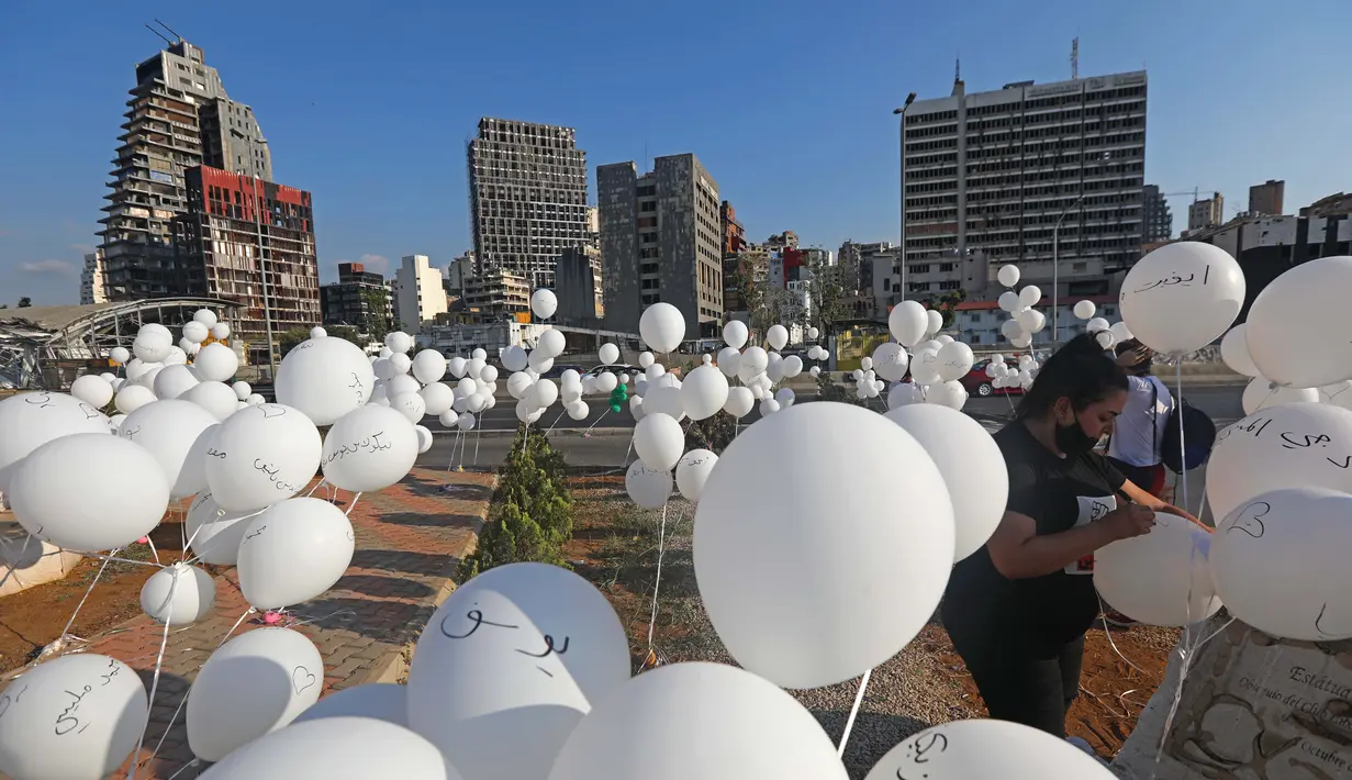 Seorang wanita menulis nama korban ledakan pelabuhan 4 Agustus pada sejumlah balon dalam upacara untuk memperingati peristiwa tersebut di Beirut, Lebanon, 4 Oktober 2020. Dua ledakan yang mengguncang Pelabuhan Beirut menghancurkan sebagian kota dan menewaskan sekitar 190 orang. (Xinhua/Bilal Jawich)